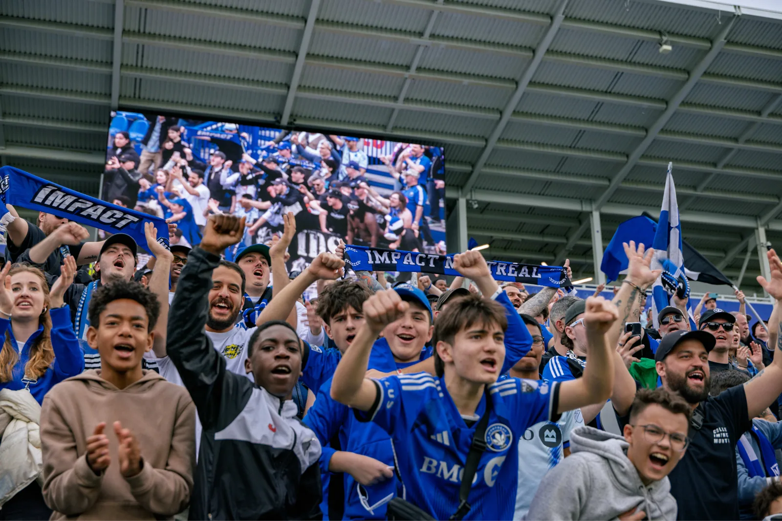 CF Montréal supporters cheering and waving scarves in the stands at Stade Saputo